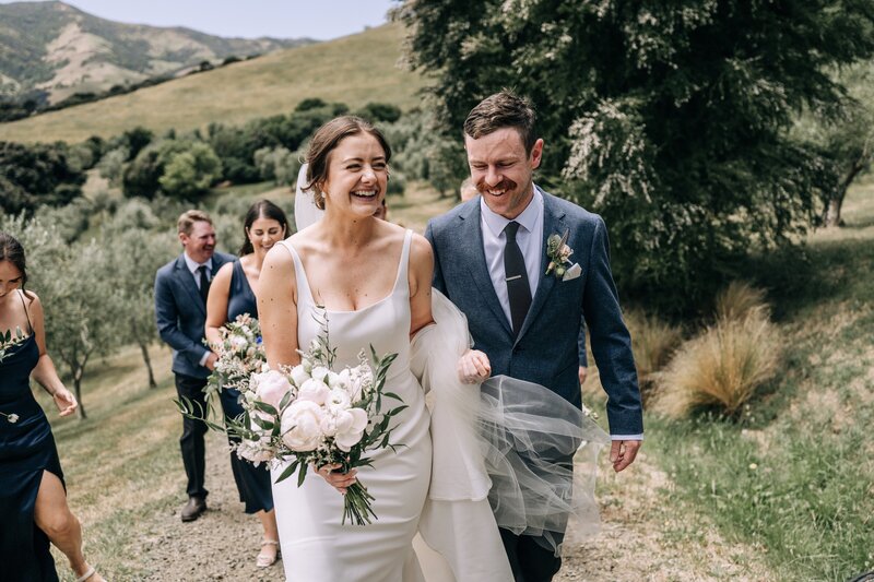 bride and groom laugh together walking up a hill in akaroa at mt vernon lodge venue