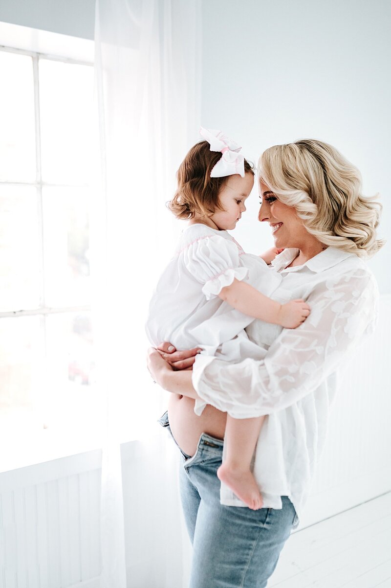 pregnant mom in white holding her toddler daughter