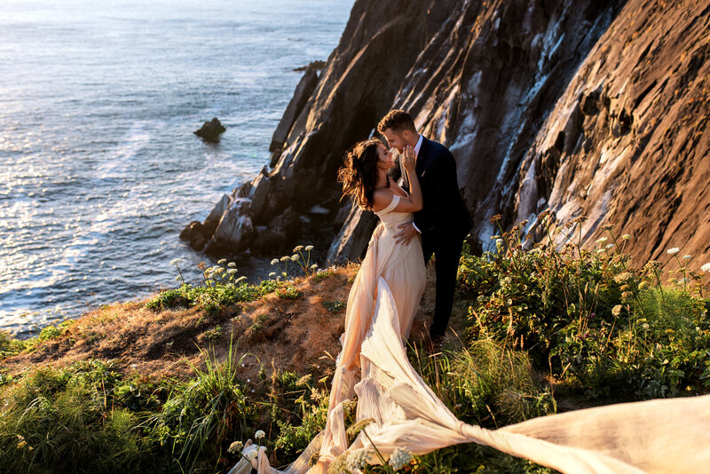 Bride standing on a cliff at sunset with her flowing dress, captured by an Oregon Coast Elopement and Wedding Photographer.