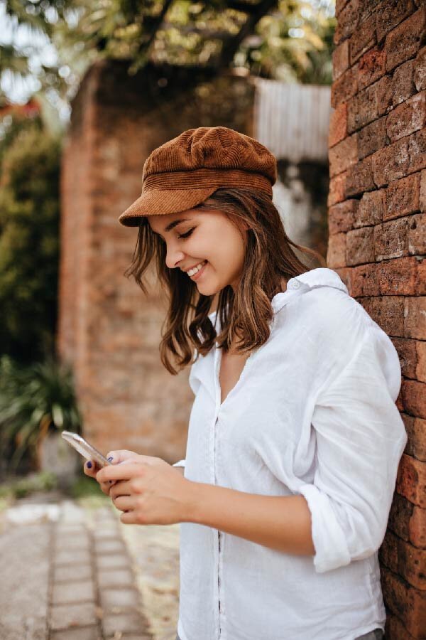 Young woman in beige linen outfit with hand oveer her face and white buildings in the backgruond | Brand By Design