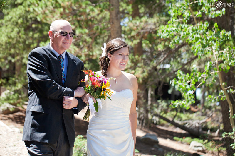 Bride walks with her dad down the trail at Panorama Point at her summer wedding at Golden Gate Canyon State Park in Colorado
