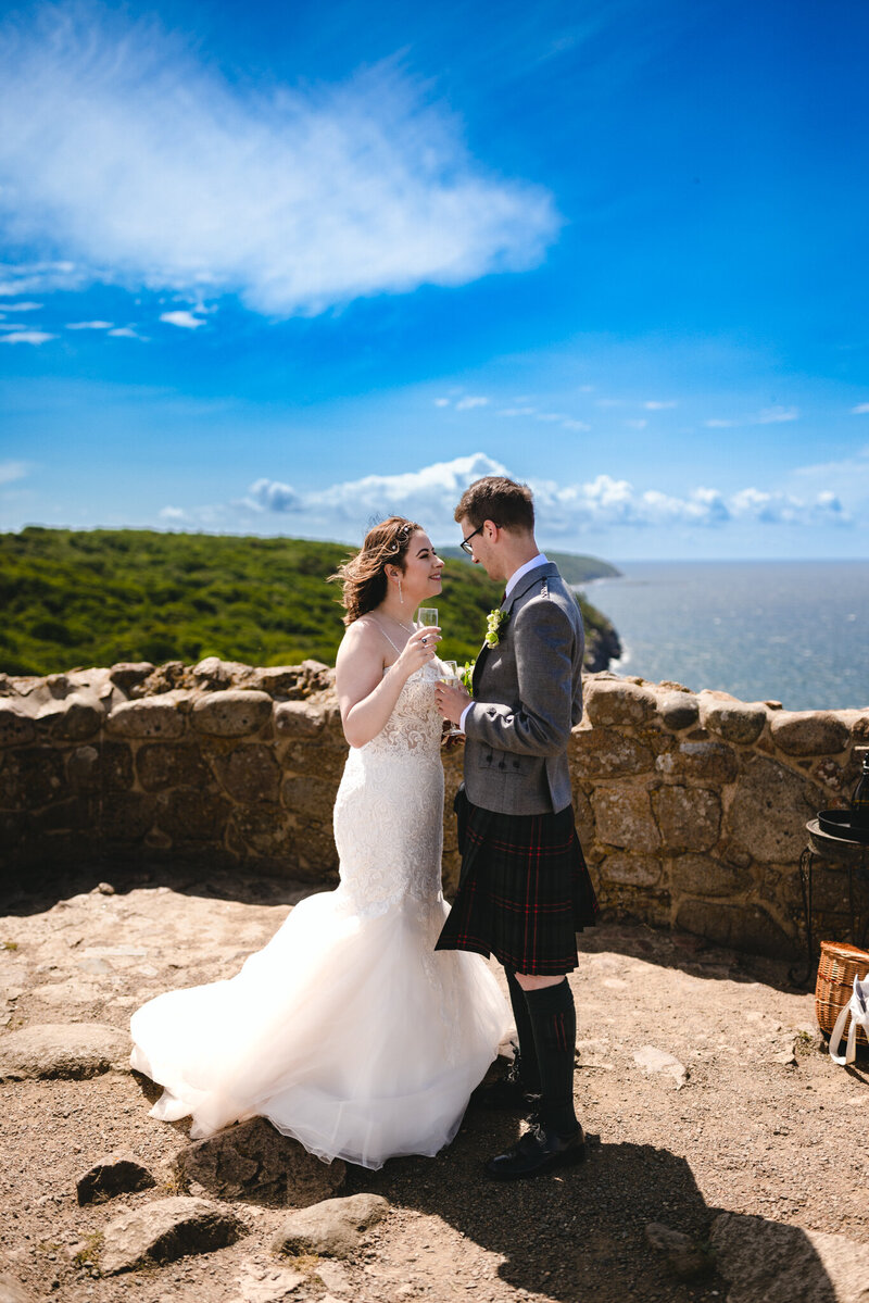 A couple toasting with the champagne on the hill of Hammershus, the best place to get married abroad and have a destination wedding