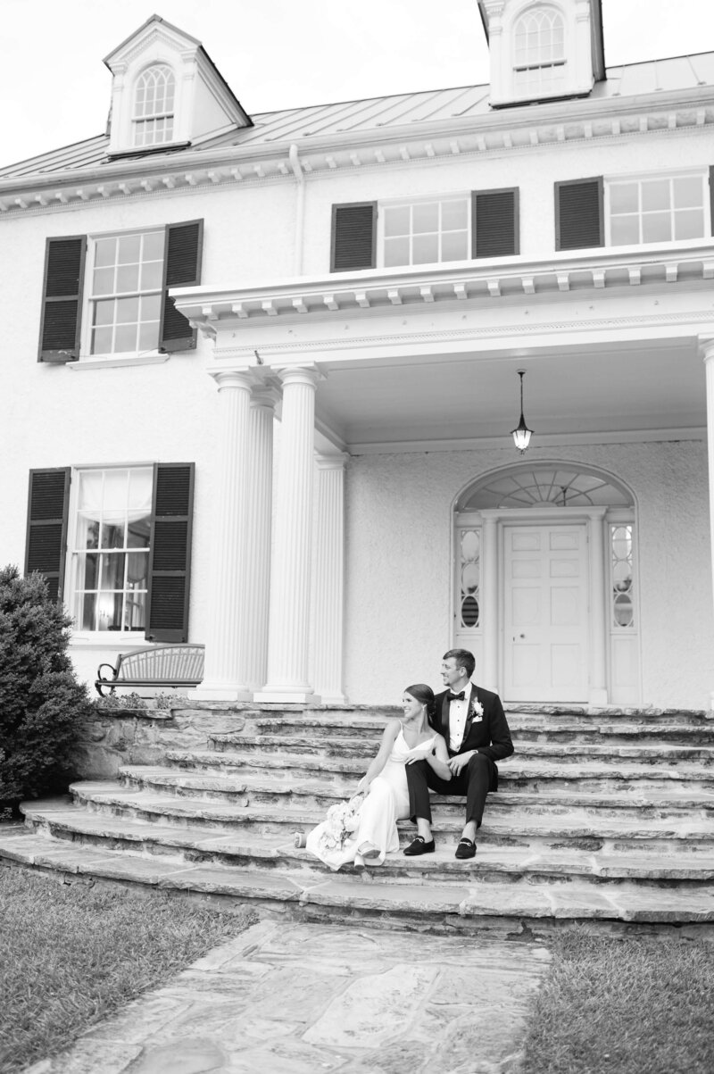 Bride and groom sit together on the steps of a historic Virginia estate, captured in a timeless and romantic style by Virginia Wedding Photographer.