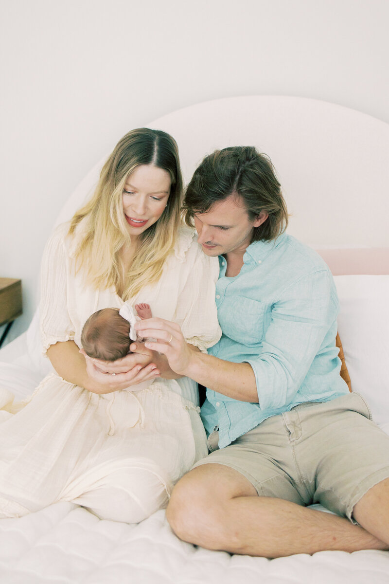 Austin newborn parents admire baby on bed.