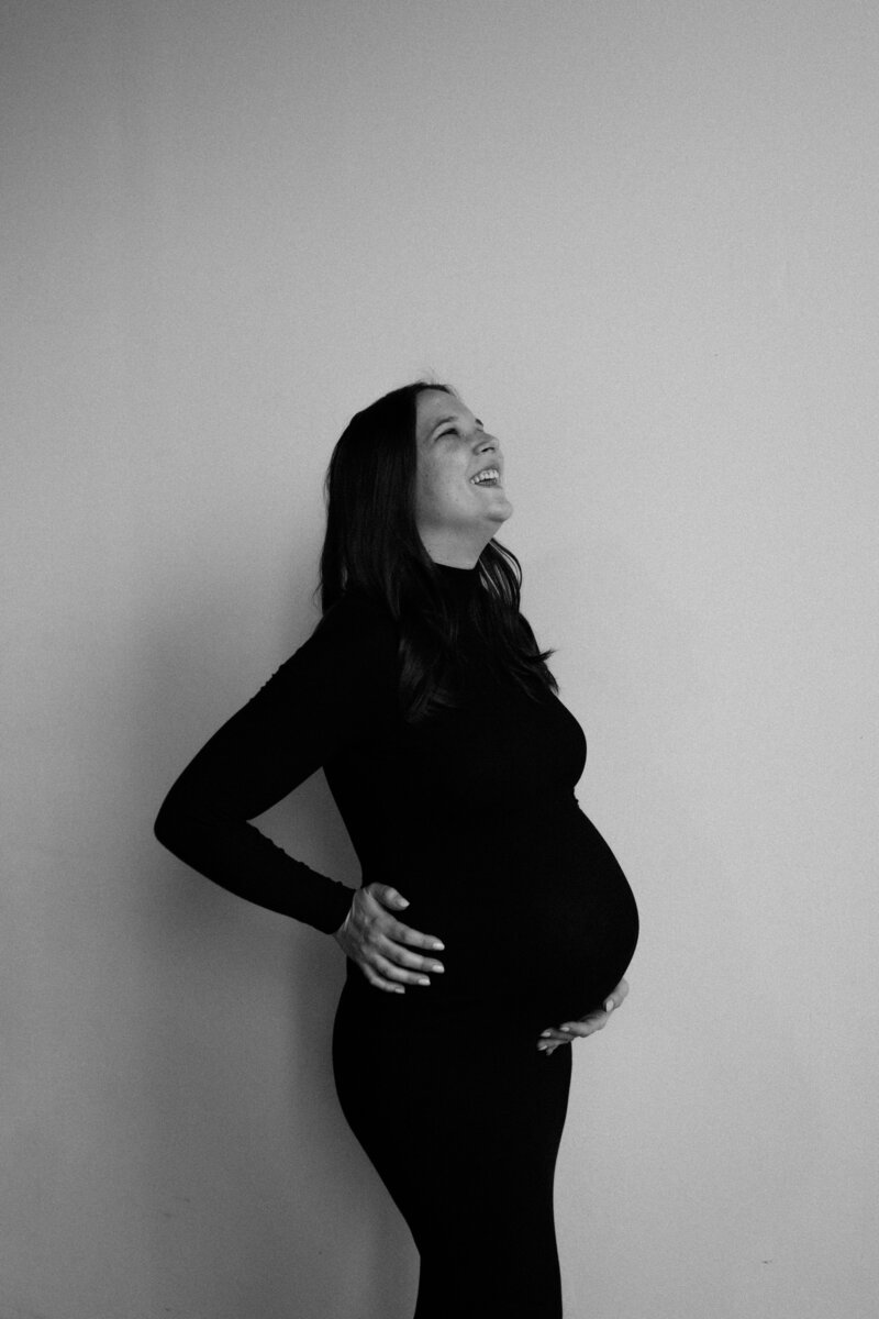A mama-to-be wears a black body-con dress during a studio maternity session photographed by Emmie Verdell Photo.