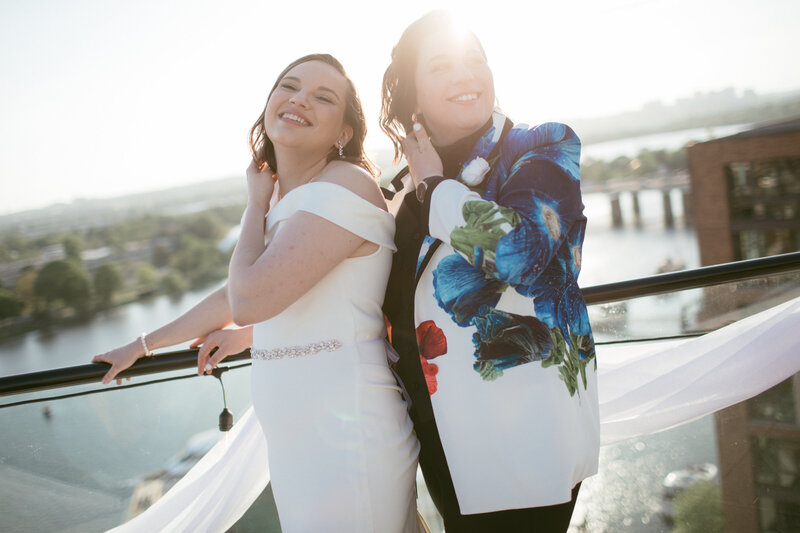 lesbian couple posing laughing and holding one another after just getting married on the terrace at La Vie in DC while the sun it setting