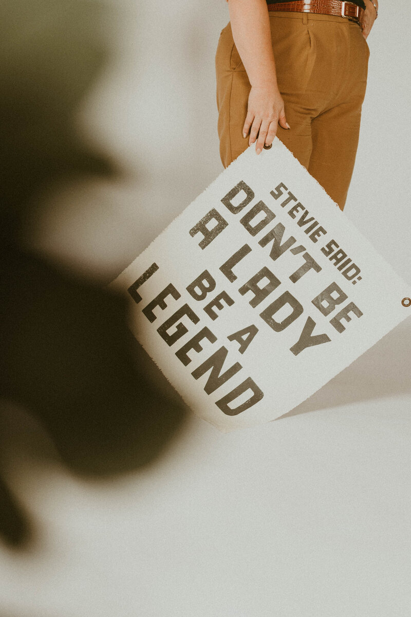 Wedding Planner holding a sign at her  side that says "Stveie says don't be a lady, be a legend"