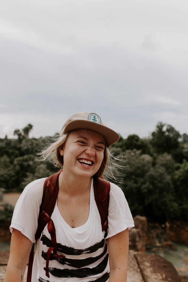 Headshot of Emma Studley wearing a hat and smiling at the camera on a hike