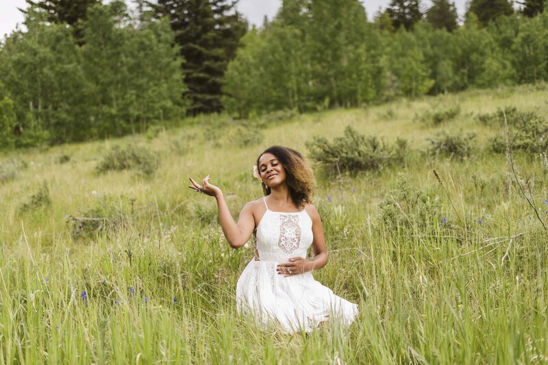 woman wearing a white dress sitting in a field with her eyes closed