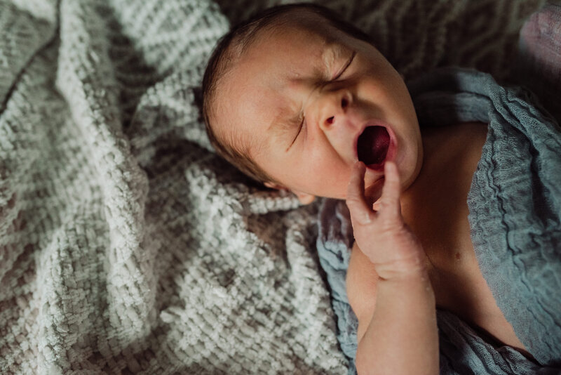 newborn baby in a blue blanket yawning