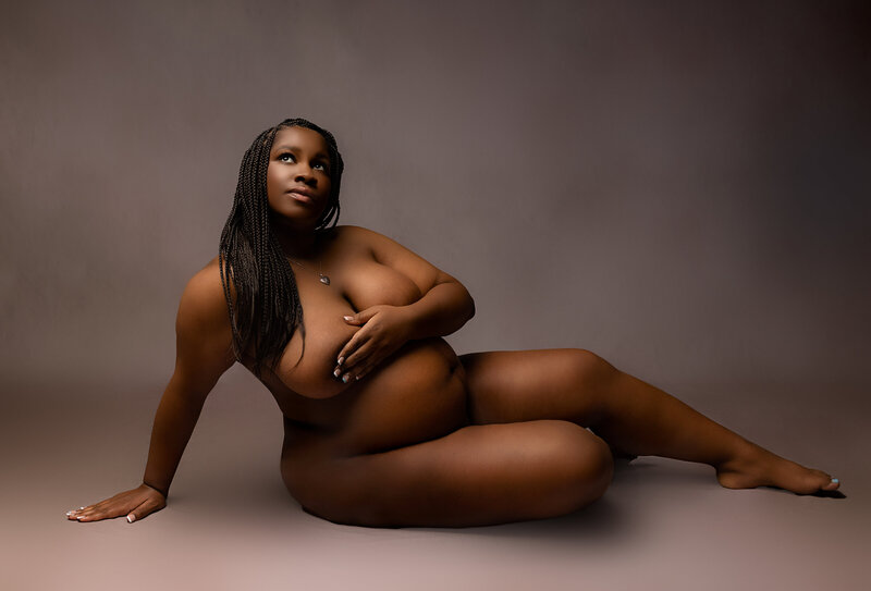 pregnant mother sitting on brown backdrop in Austin studio