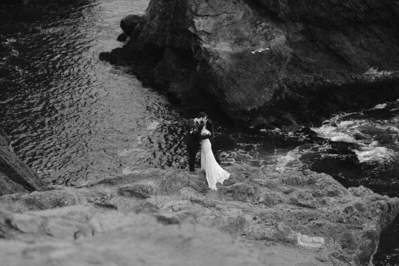black and white image bride and groom on rocks