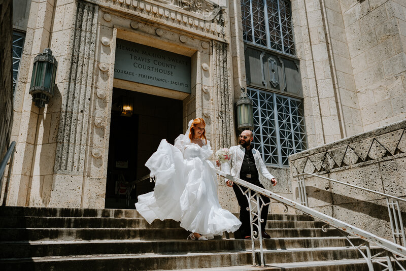 couple running down steps of courthouse after eloping