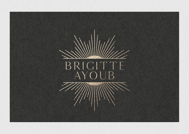 Gold foil logo with text "Brigitte Ayoub" and sun ray illustration