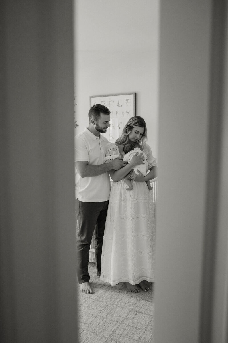 New parents cuddling their newborn baby during an intimate in-home lifestyle session in New York City