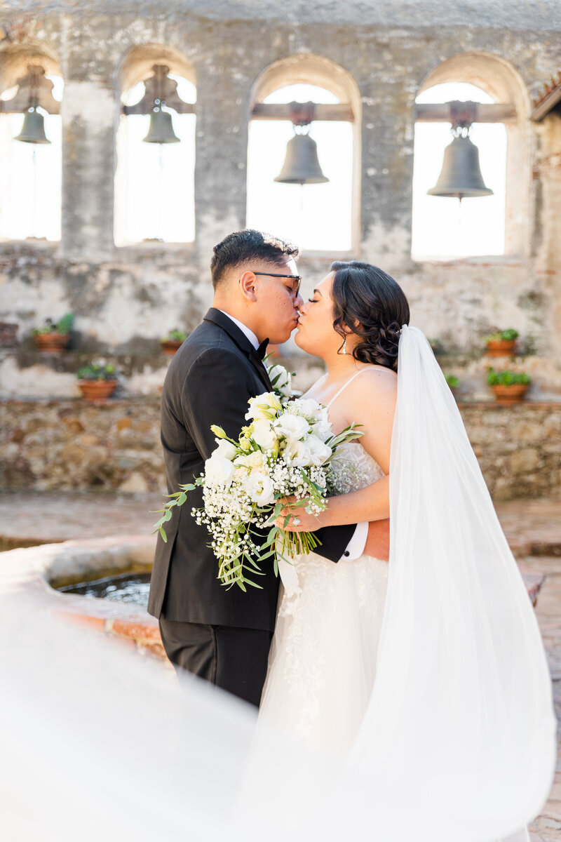 Bride and groom kissing at San Juan Capistrano Mission