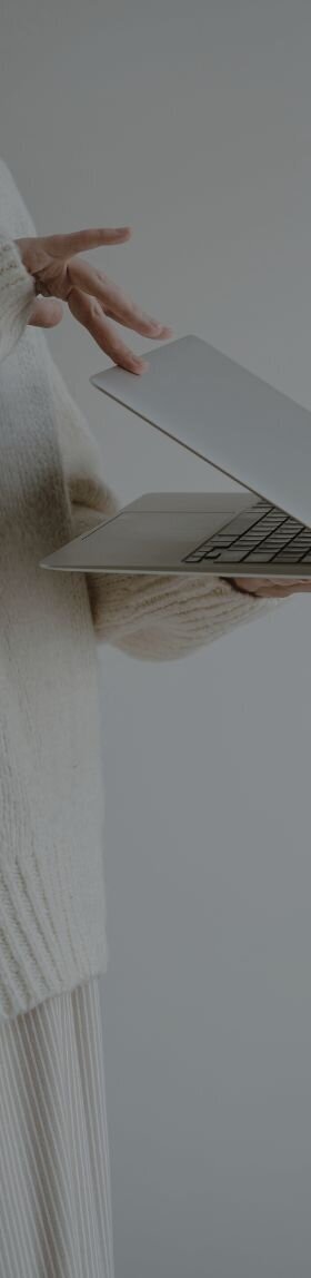 a person standing with a laptop in their hands and closing the laptop