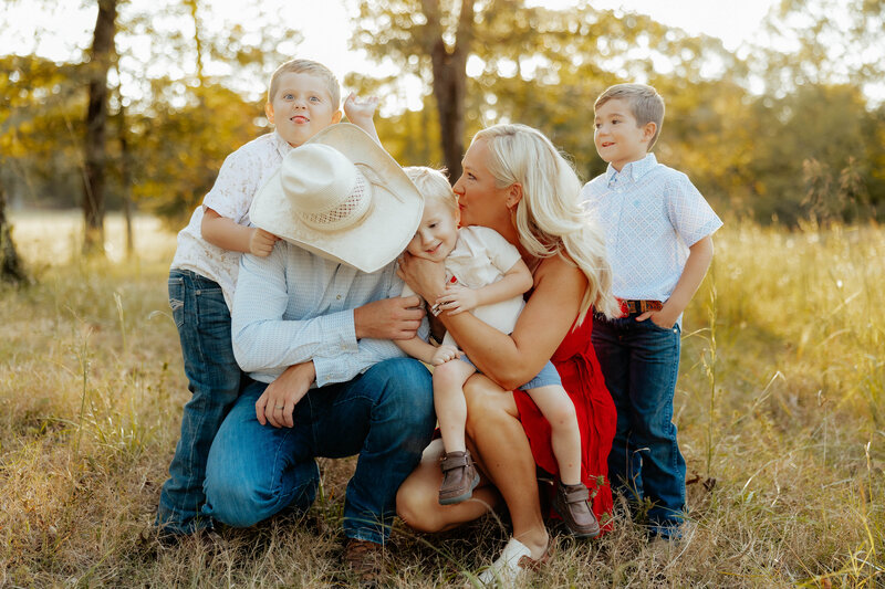 outdoor family session with mom and dad swinging baby in blanket between them