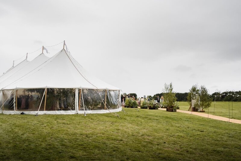 A large pole marquee in white with clear walls on a green lawn