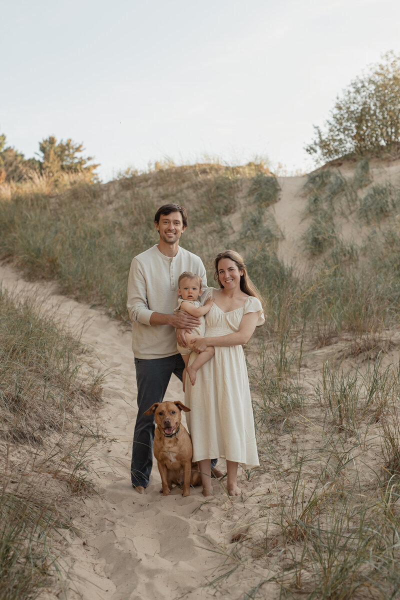 Family walking with toddler and dog on sandy trail photographed by a family photographer in Grand Rapids