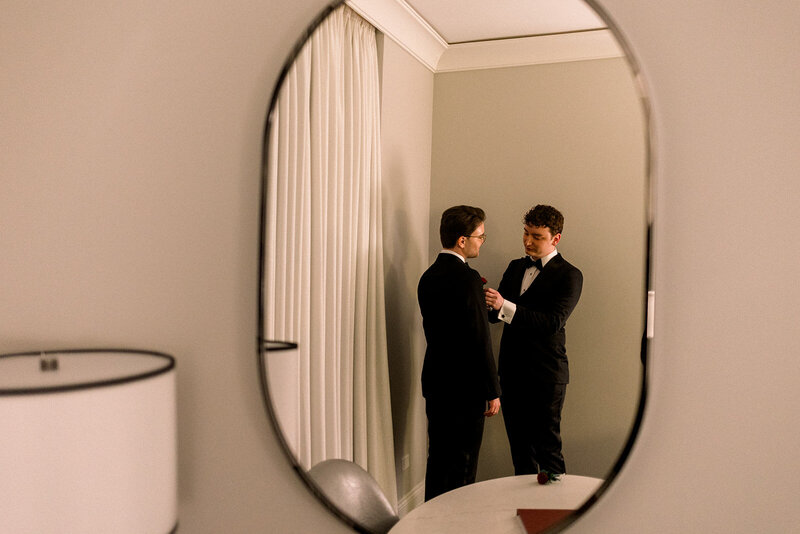 two grooms in hotel room mirror