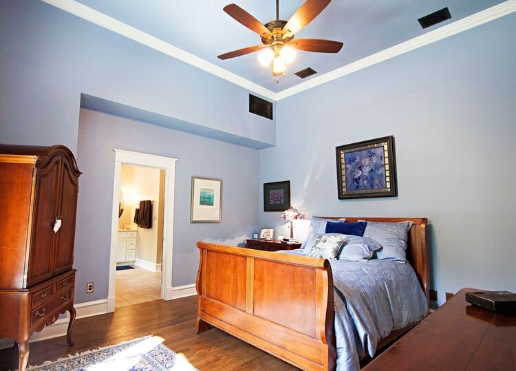 elegant bedroom with white crown molding and wooden ceiling fan. hardwood bedroom floors.