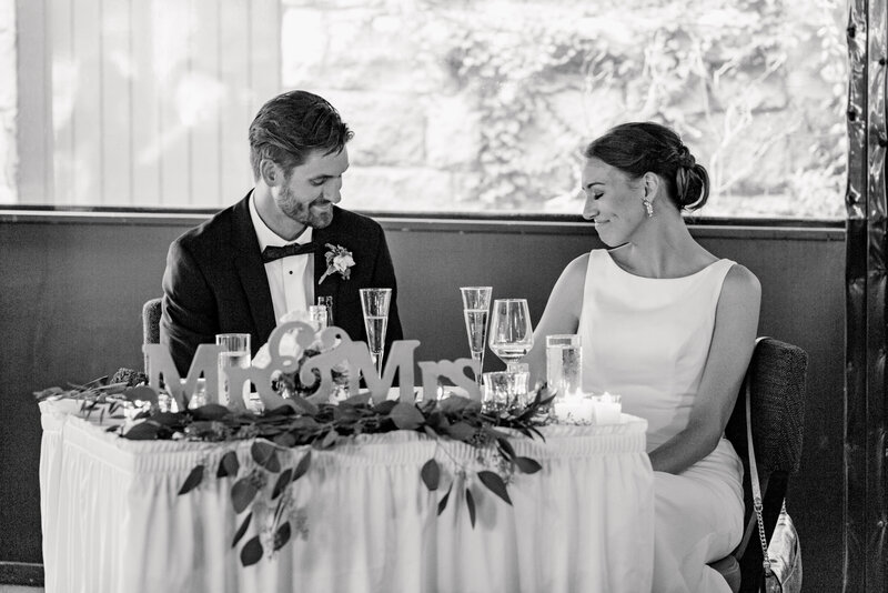 Black and white portrait of the bride and groom at the sweetheart table