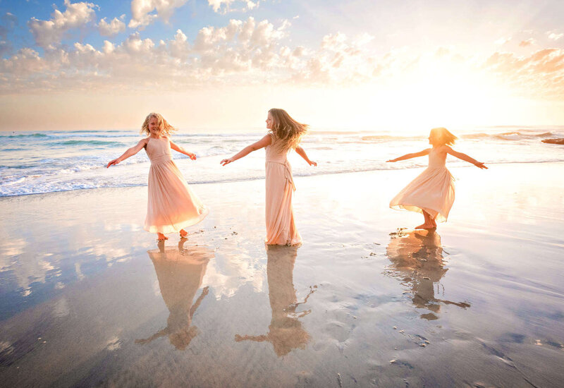 Three girls spinning in the ocean at their Carlsbad family photography session