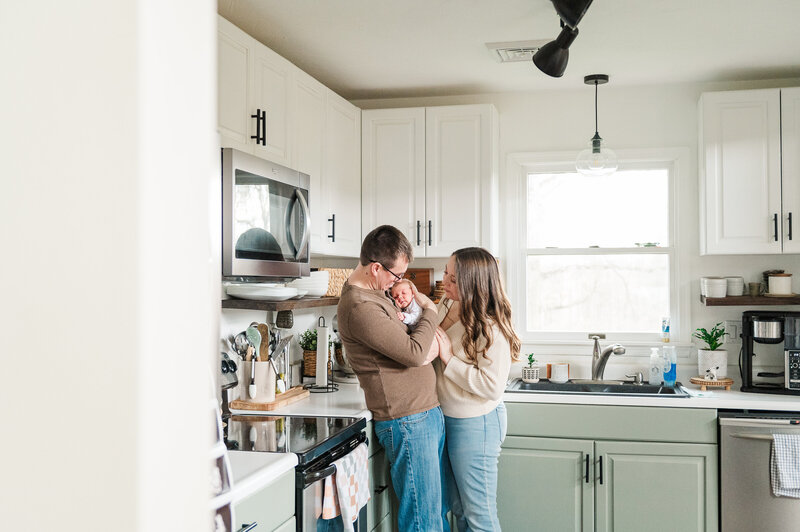 New mother and father holding their newborn baby in their kitchen by york pa photographer