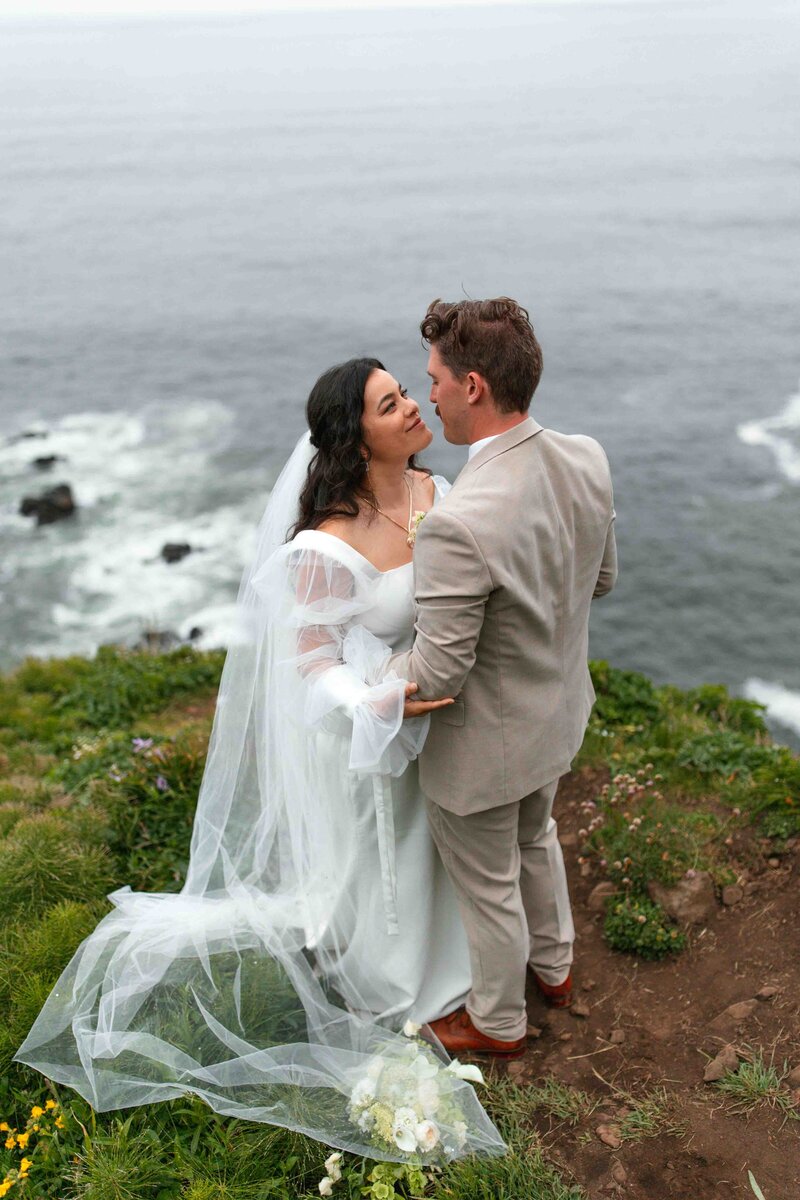 a wedding couple stand at a cliff edge exchanging their vows during their elopement at Elk Flats on the Oregon Coast