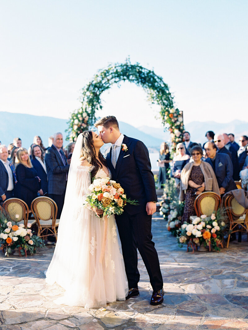 Bride in deep v back wedding dress holding wedding bouquet filled with colorful garden roses for fall Lake Chelan wedding