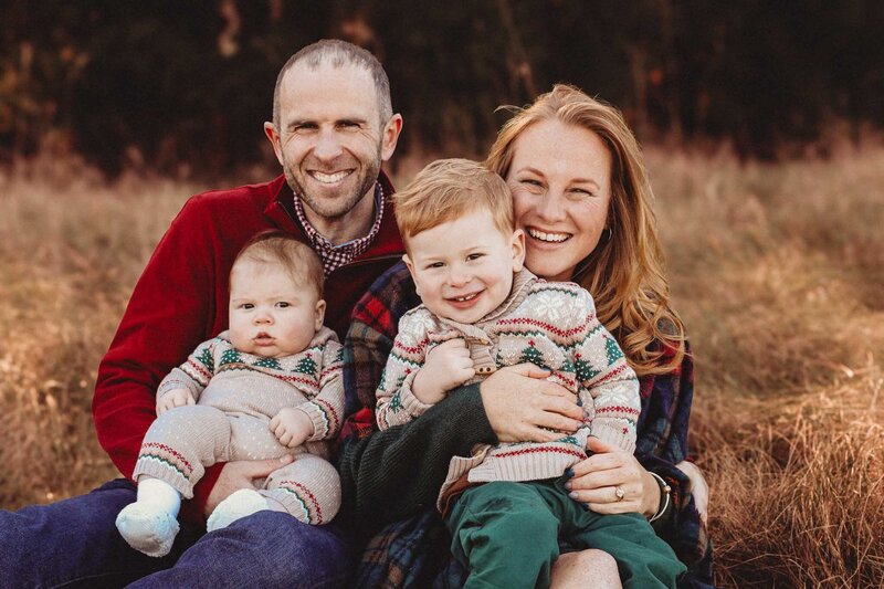 Happy little family posing in field during mini session photoshoot.