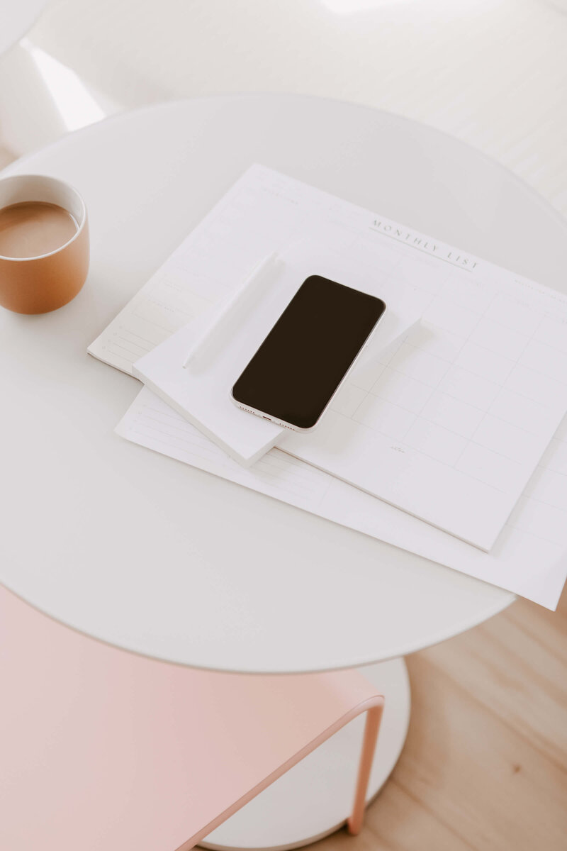an iphone laying on the table stacked on white notebooks can be used as a iphone mockup stock photo