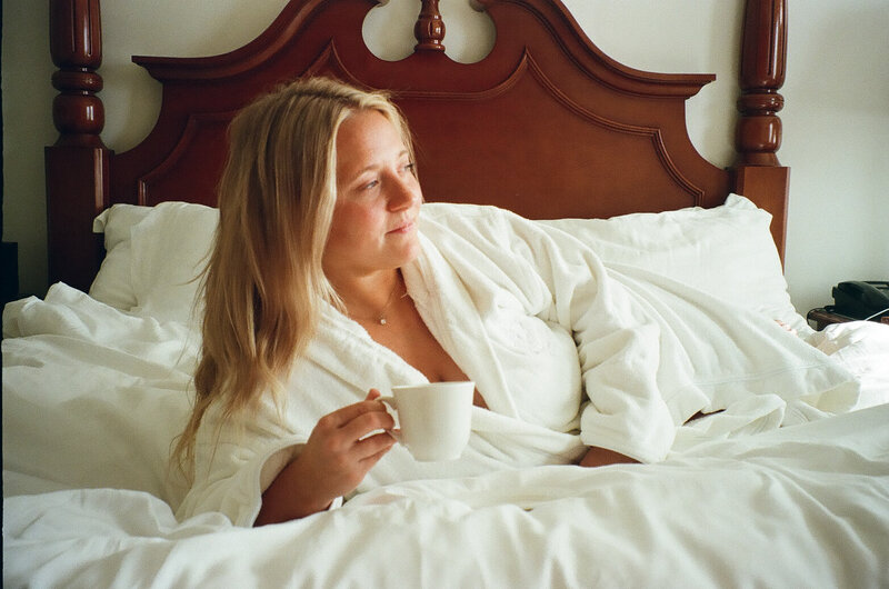 Kaylea Georgia destination wedding photographer laying in bed with coffee in hand