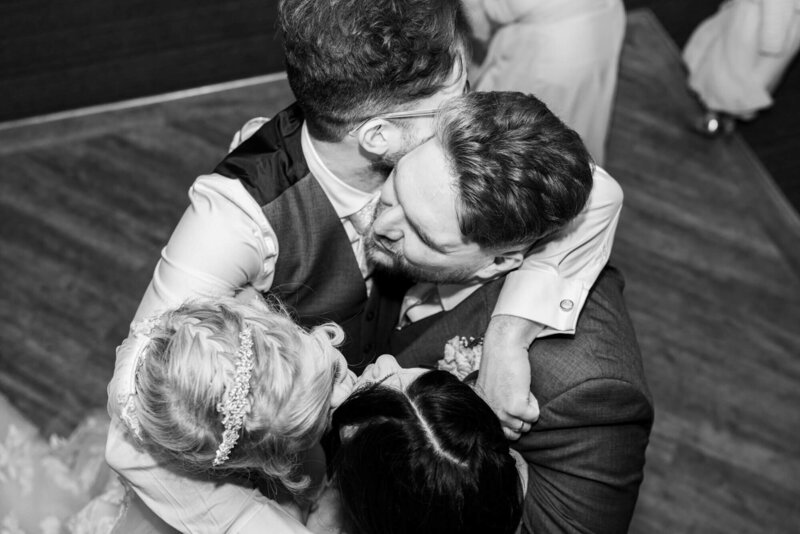 Yorkshire Wedding Photographer & Videographer capturing an emotional black and white wedding hug between the groom, bride, best man and bridesmaid at Chevin Hotel and Spa.