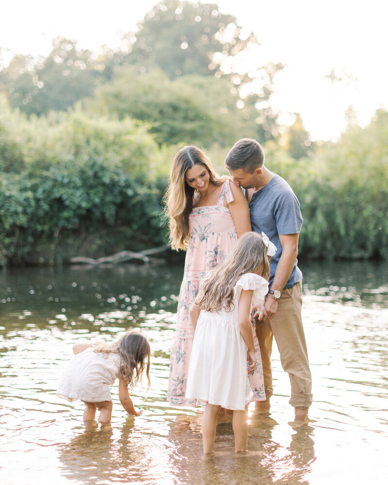 Parents and young daughters explore a creek during family portrait session