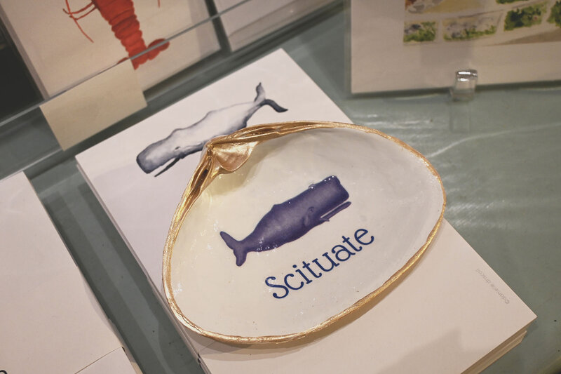 Oyster tray with "Scituate" painted on it on top of a notebook with a whale