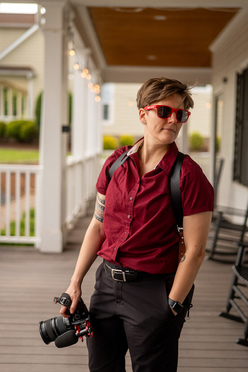 A photographer holding a camera with sunglasses on