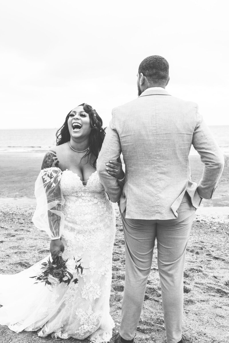 bride laughing with groom on the beach
