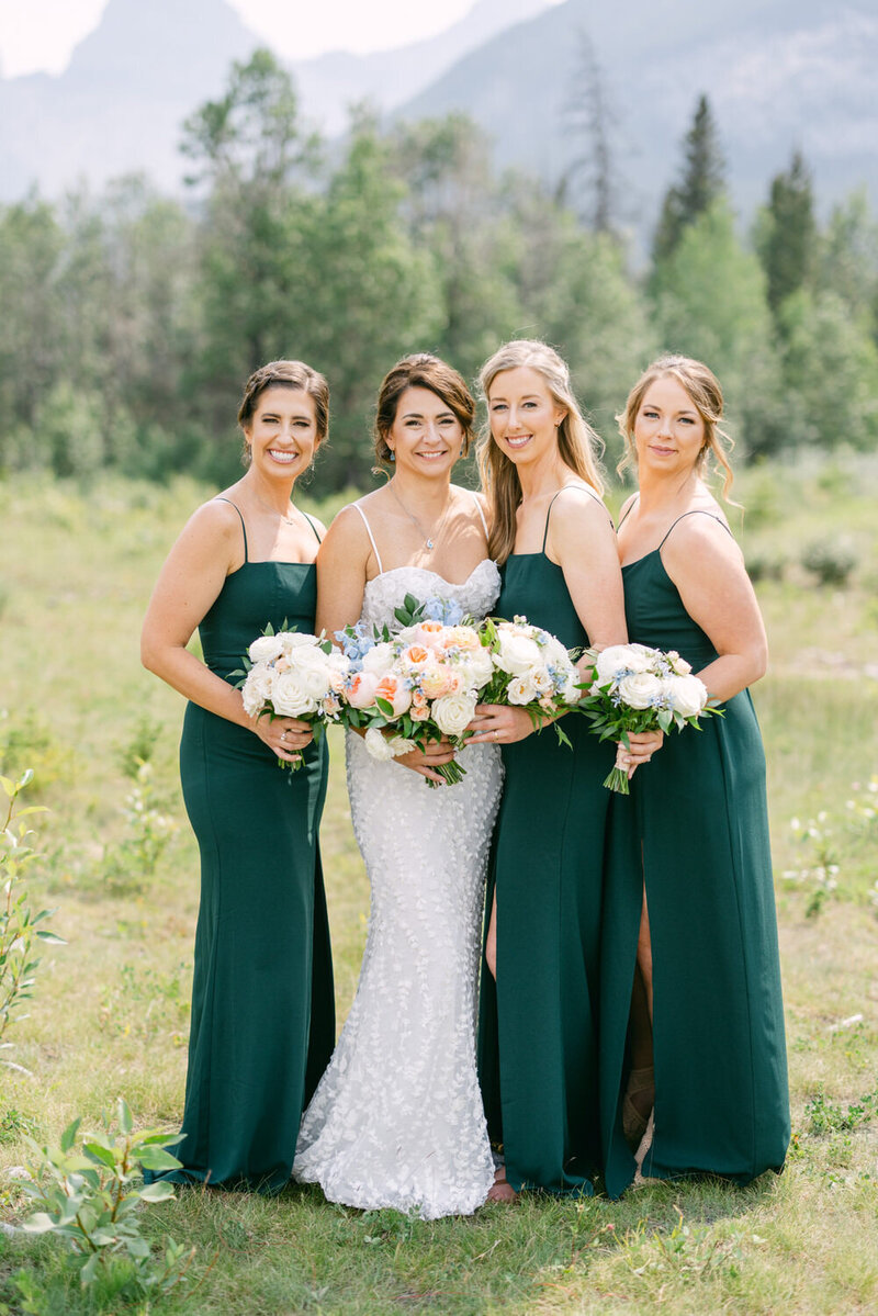 This image captures the joyful expressions of bridesmaids during their portrait session in Canmore. Surrounded by natural beauty, their smiles reflect the happiness and excitement of the bridal party on this special day.