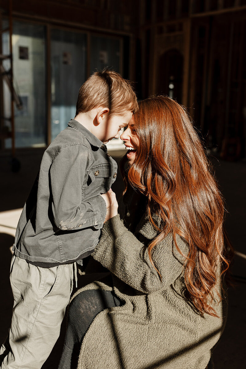Photo of a mom holding her son and laughing in their home at golden hour 
