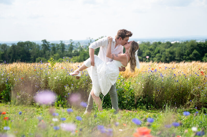 A couple poses for engagement pictures in front of a wooden fence in a field in Leesburg VA