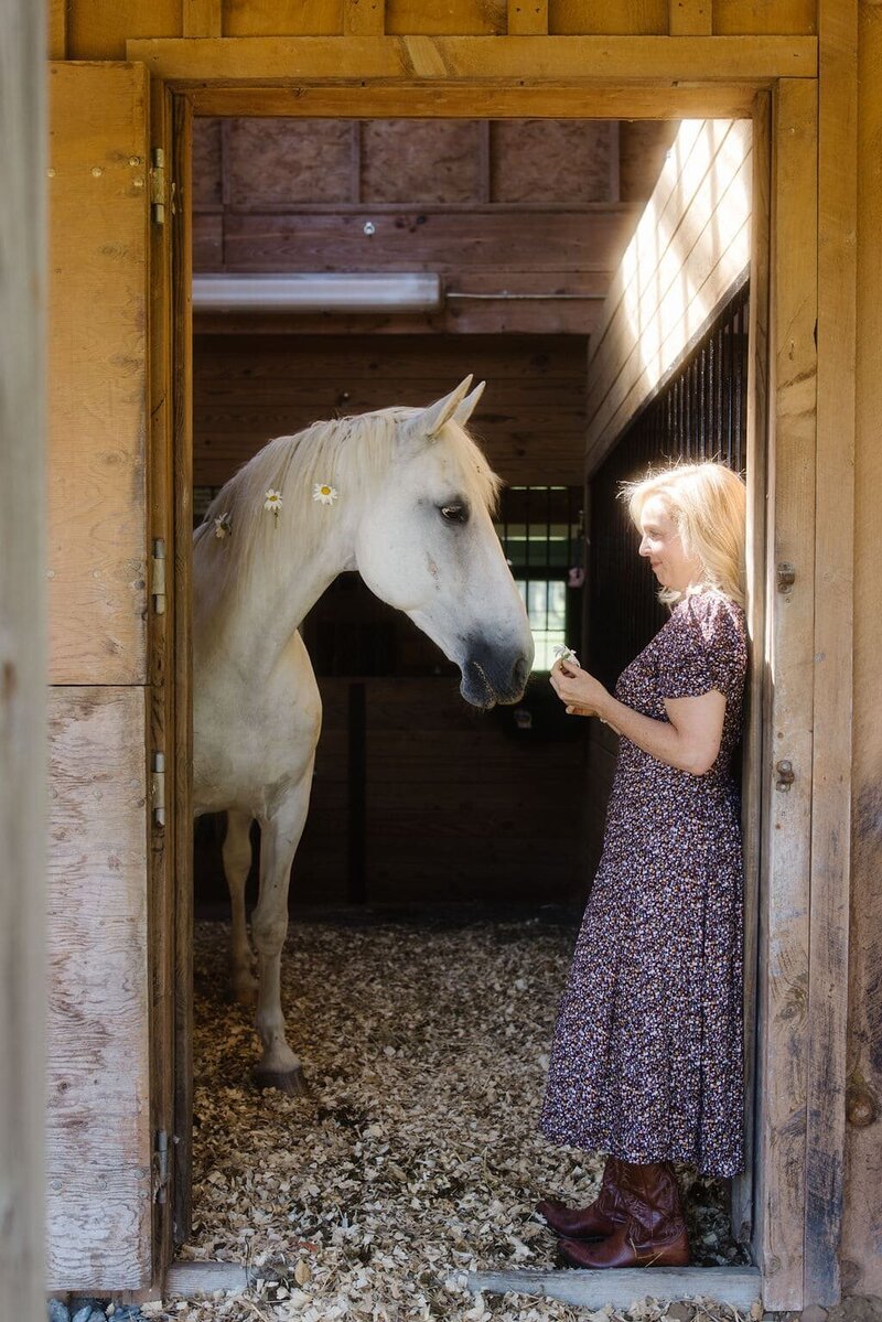 Leiko connecting with a horse inside a barn during an equine-guided healing session