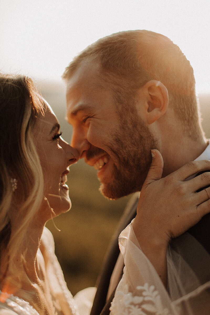 Bride and groom leaning in for a kiss and smiling