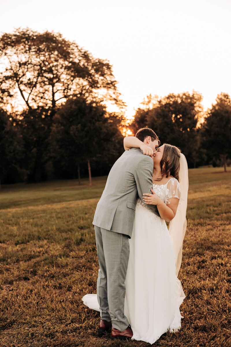bride and groom kissing at sunset