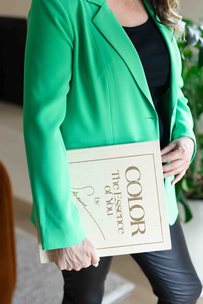 Color psychology book titled 'The Essence of You' held against emerald green blazer, showcasing brand strategy resources and expertise