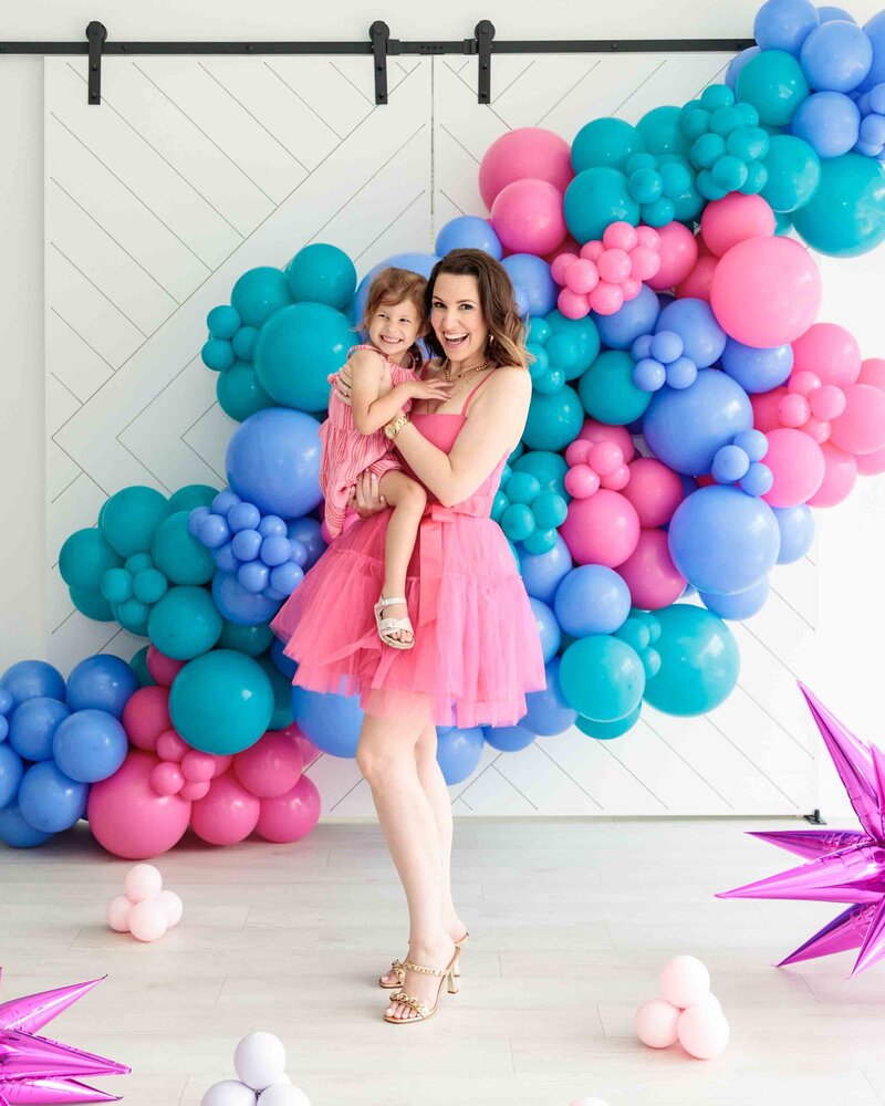 The Balloon Expert at Air with Flair Decor, adorned in a charming pink dress, sharing magical moments with her daughter. Our expert team brings a personal touch to balloon artistry, creating joyous experiences for all.