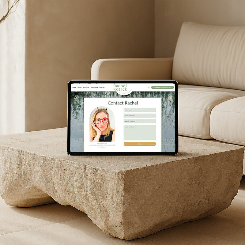An iPad sits on a coffee table in a cozy living room, inviting users to explore the contact page.