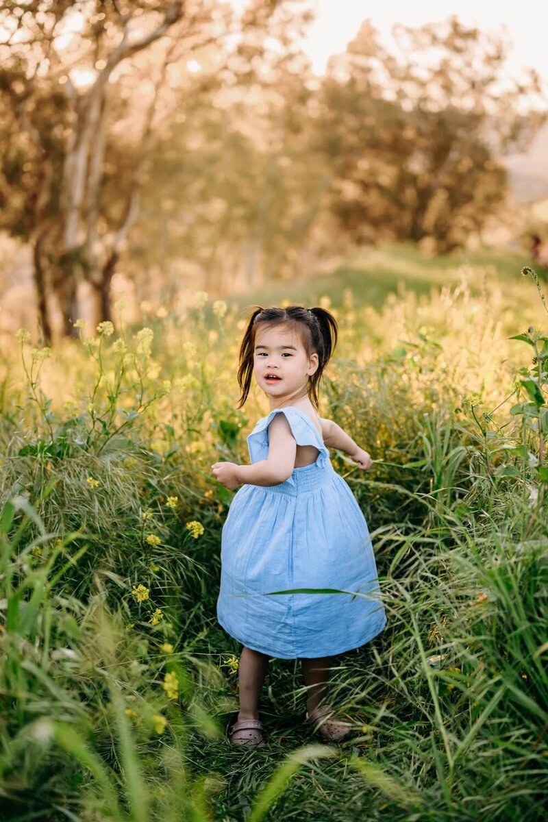 young girl looks back at the camera as she runs through a wildflower field in lafayette ca
