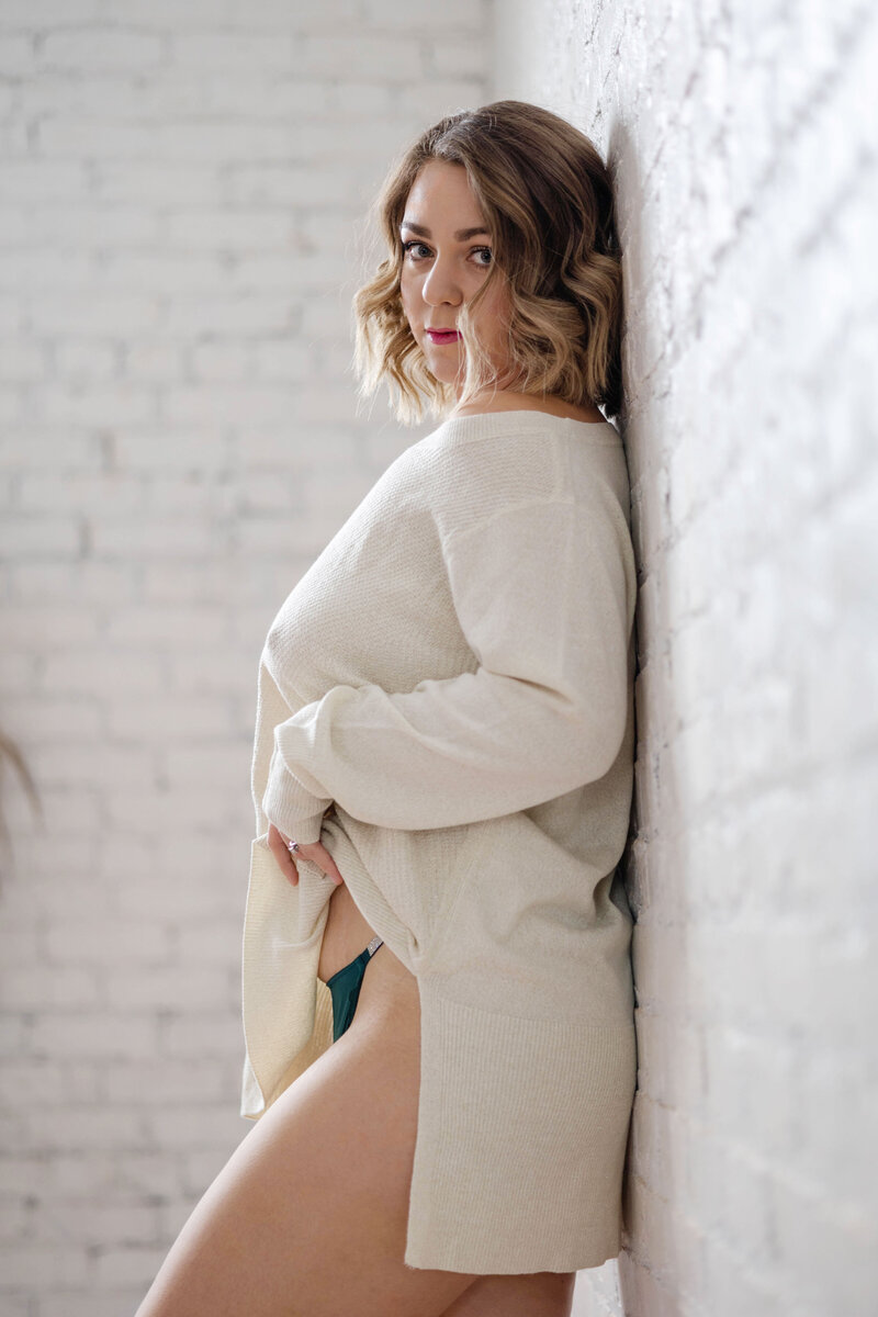 Colorado Springs Boudoir Photographer in sweater against wall